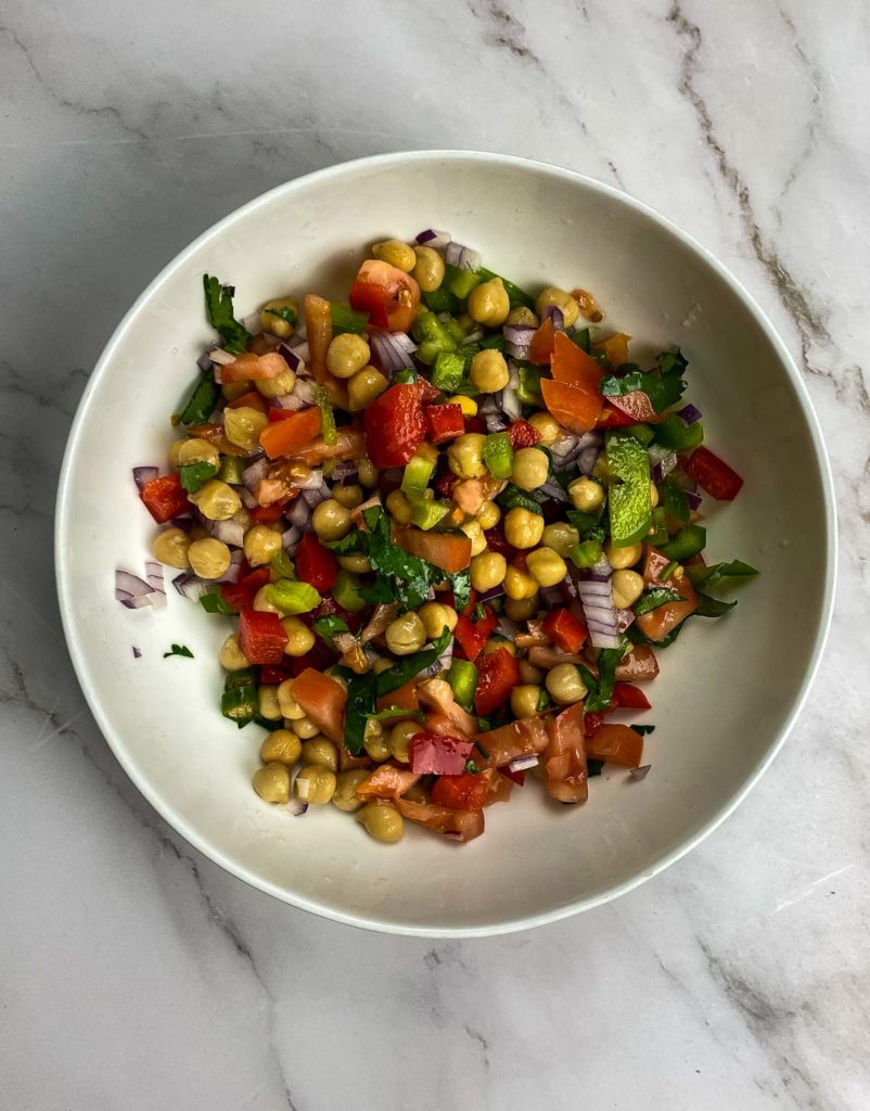 Bowl with chickpeas, tomatoes, red capsicum, red onions, green chilies