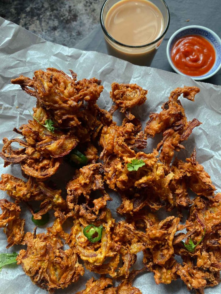 Onion Fritters On Paper With Tea And Dipping Sauce