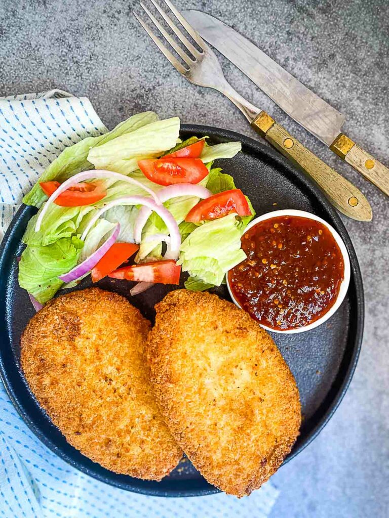 air fryer frozen breaded chicken breast in plate with salad