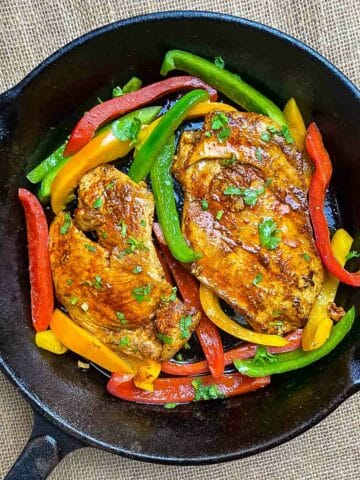 Pan-fried chicken breast with colored vegetables in cast iron