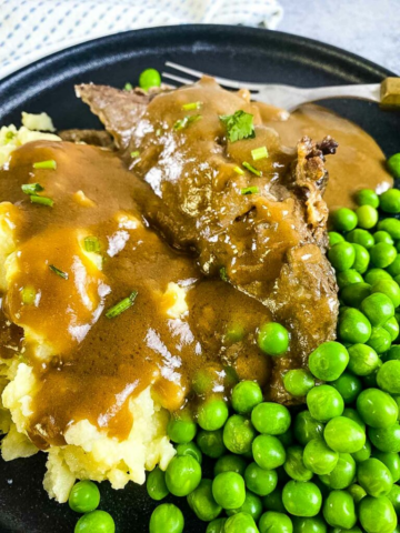 Roasted lamb with potato mash, peas and gravy on a plate.
