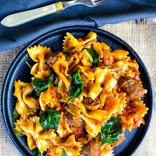 Pasta with sausages in tomato sauce in a plate.
