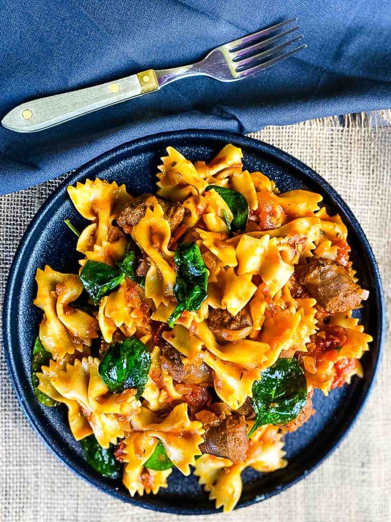 Pasta with sausages in tomato sauce in a plate.