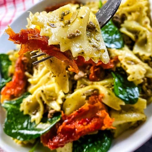 Pasta with pesto and tomatoes in a bowl with fork.