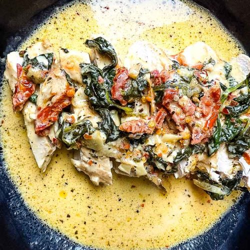 Creamy Keto Tuscan garlic chicken with sun-dried tomatoes and spinach in a skillet