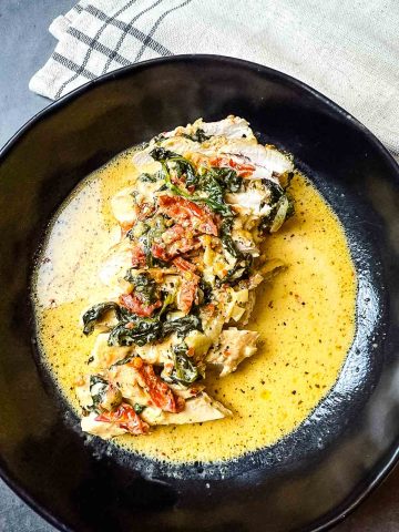 Creamy Keto Tuscan garlic chicken with sun-dried tomatoes and spinach in a skillet