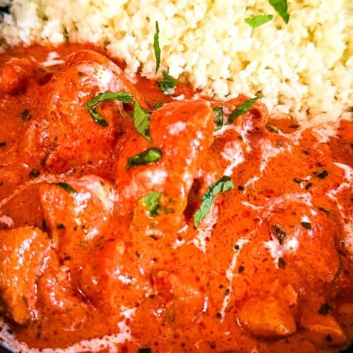 Creamy keto butter chicken in a rich tomato sauce with a butter finish and cilantro garnish with rice