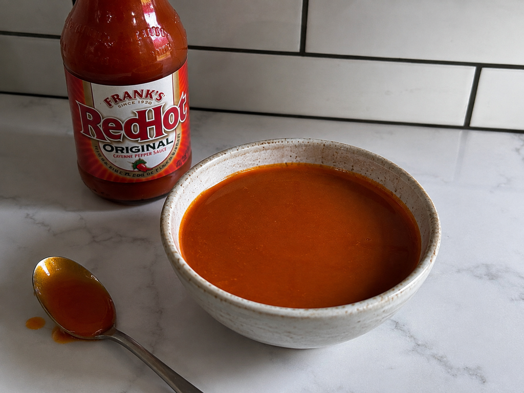 Homemade buffalo sauce in a bowl on a marble countertop