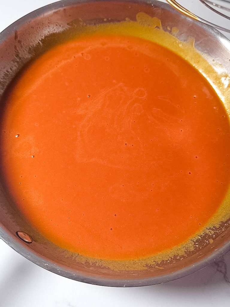 Buffalo sauce gently warming in a saucepan Smooth homemade buffalo sauce ready to serve